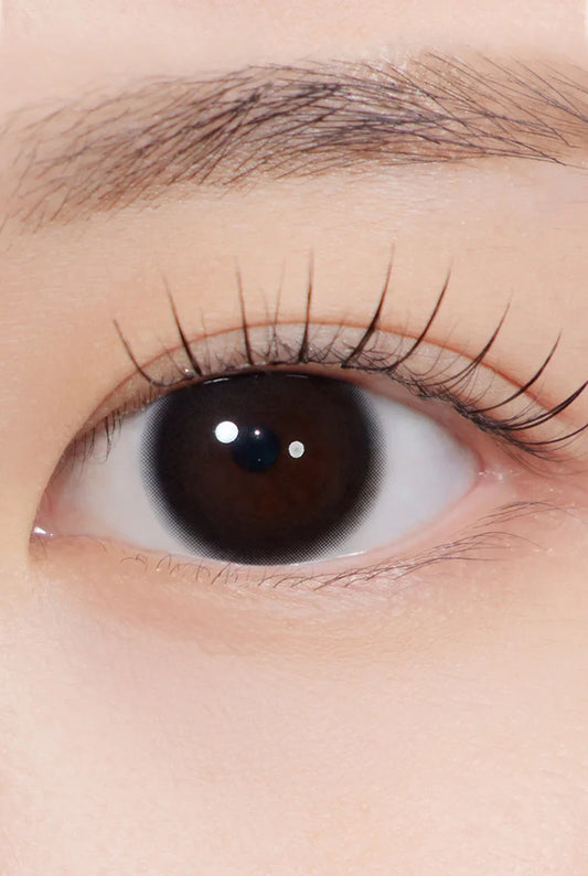 close-up of eye wearing black colored cosmetic contact lens with natural makeup